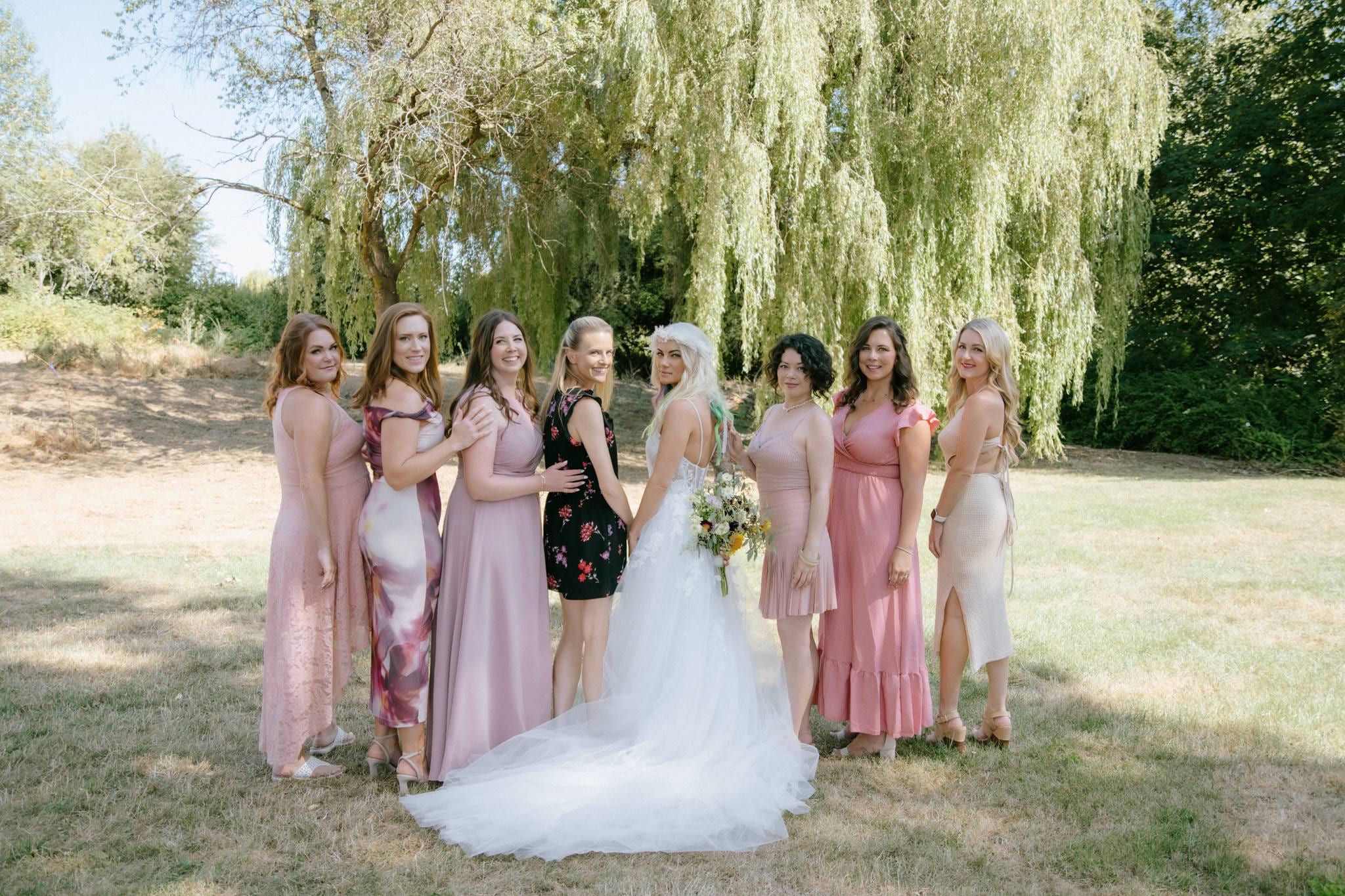 Bride and bridesmaids beneath a willow tree with their bouquets