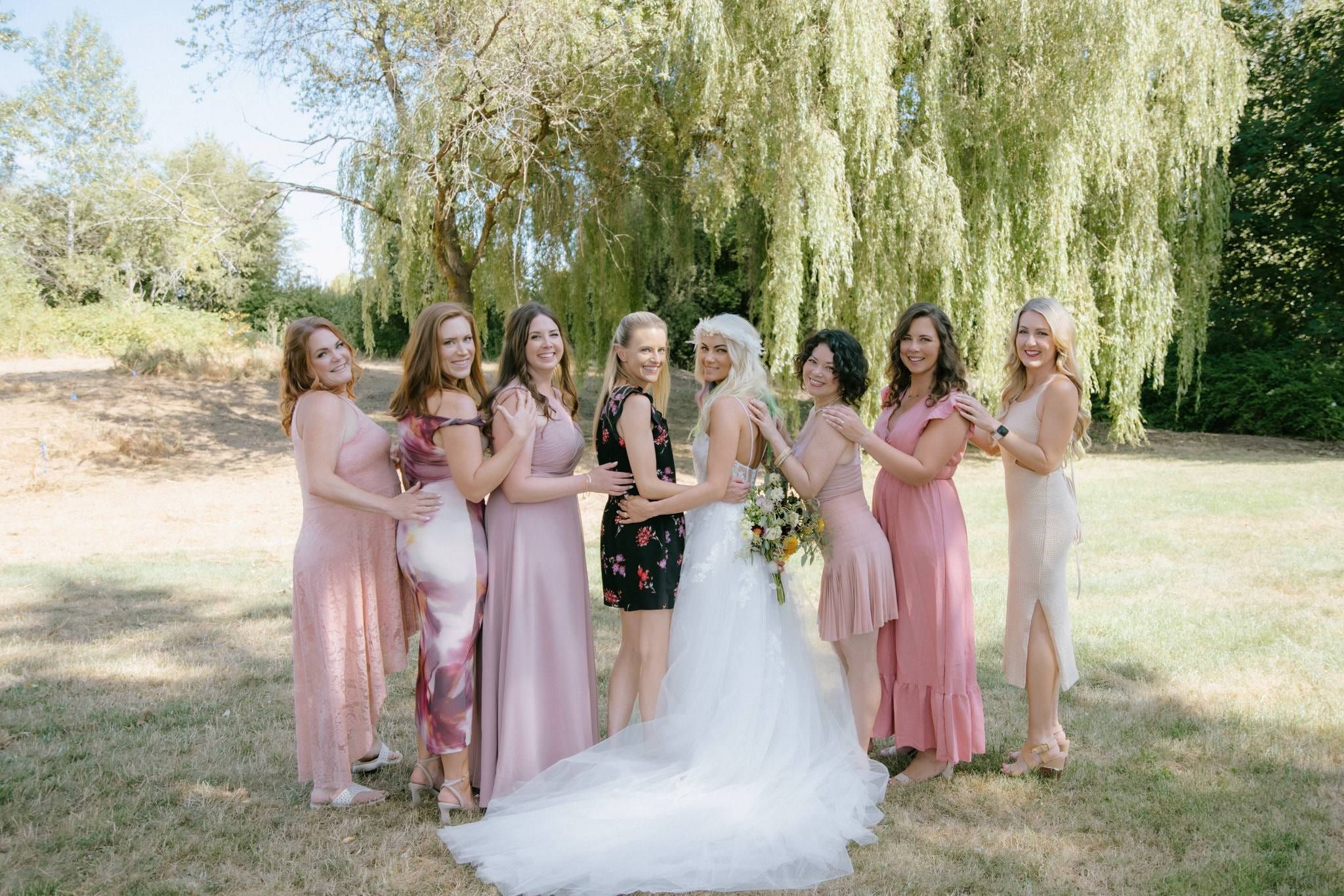 Bride and bridesmaids in pink dresses beneath a willow tree