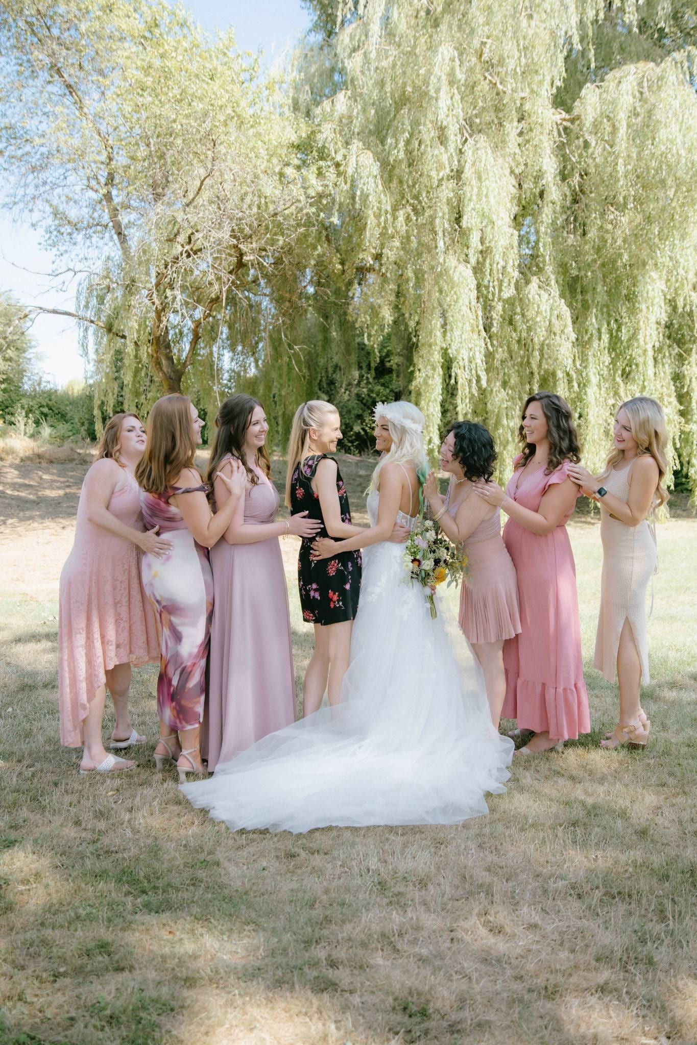 Bride with bridesmaids in pink dresses under a willow tree