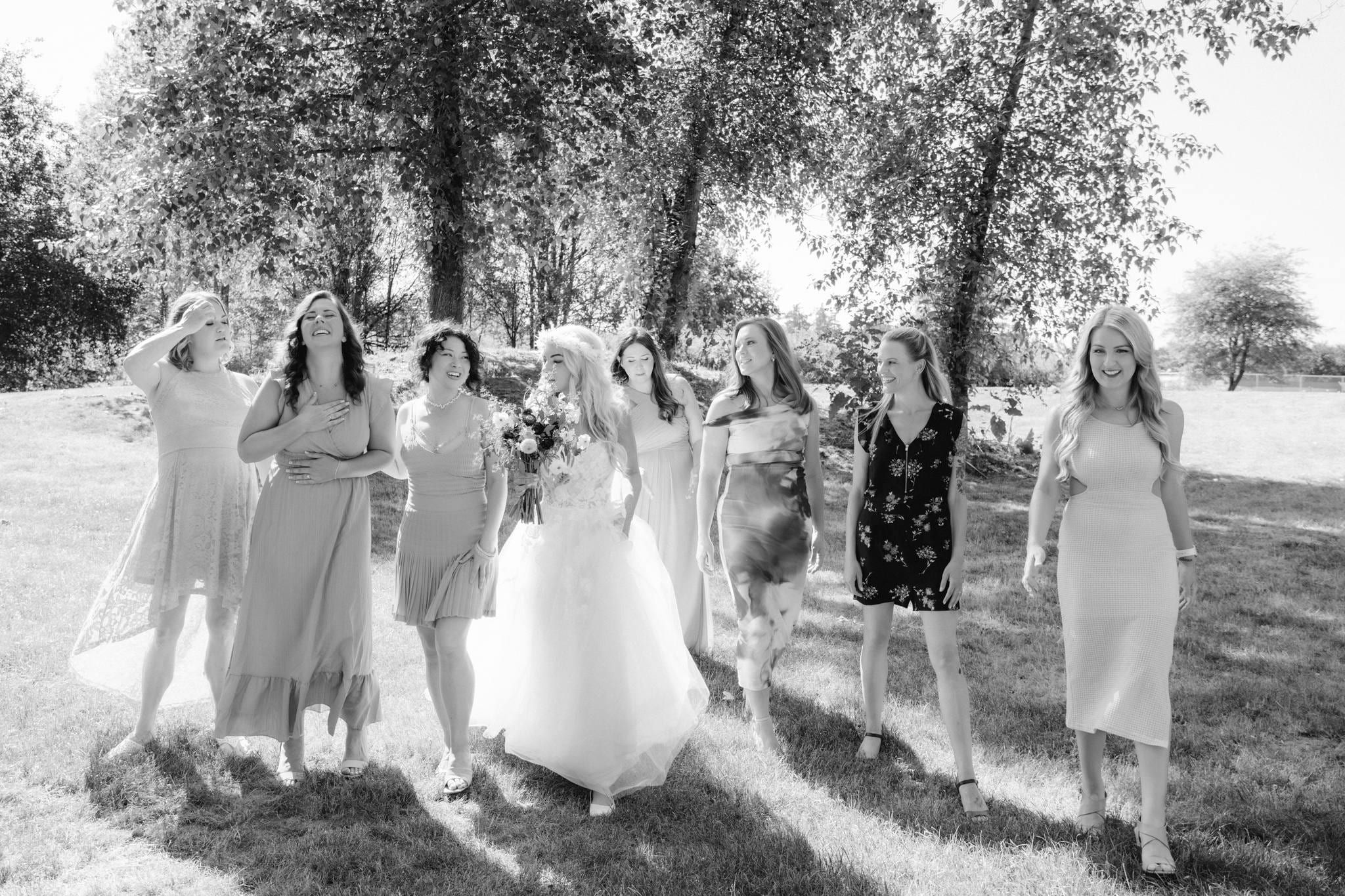 Black-and-white photo of the bride with her bridesmaids beneath the trees