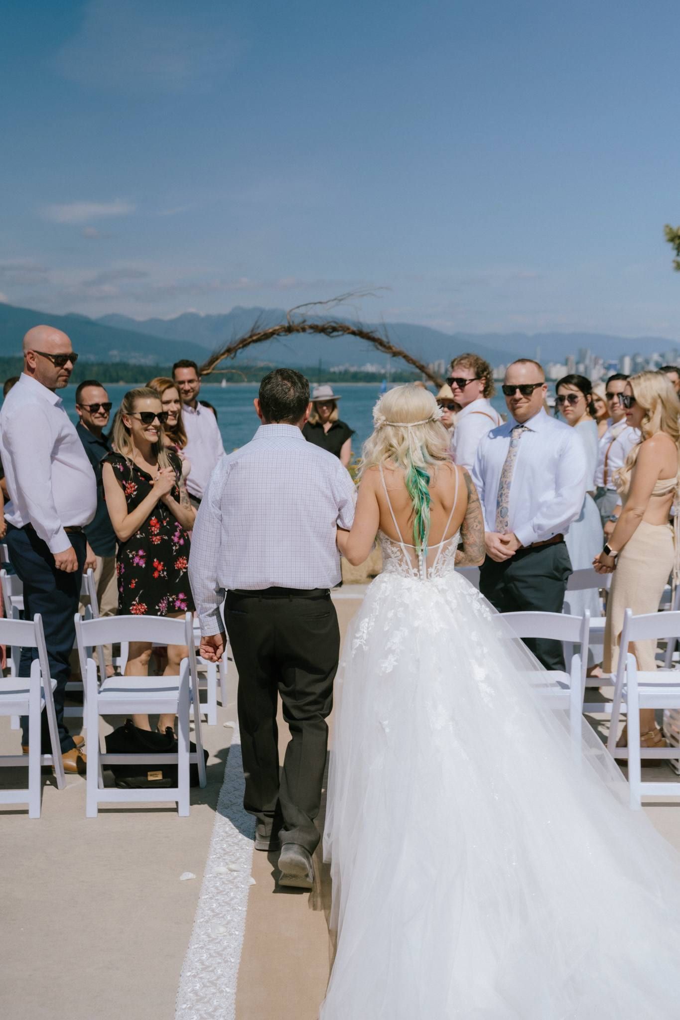 Bride walking down the aisle toward the groom under the driftwood arch