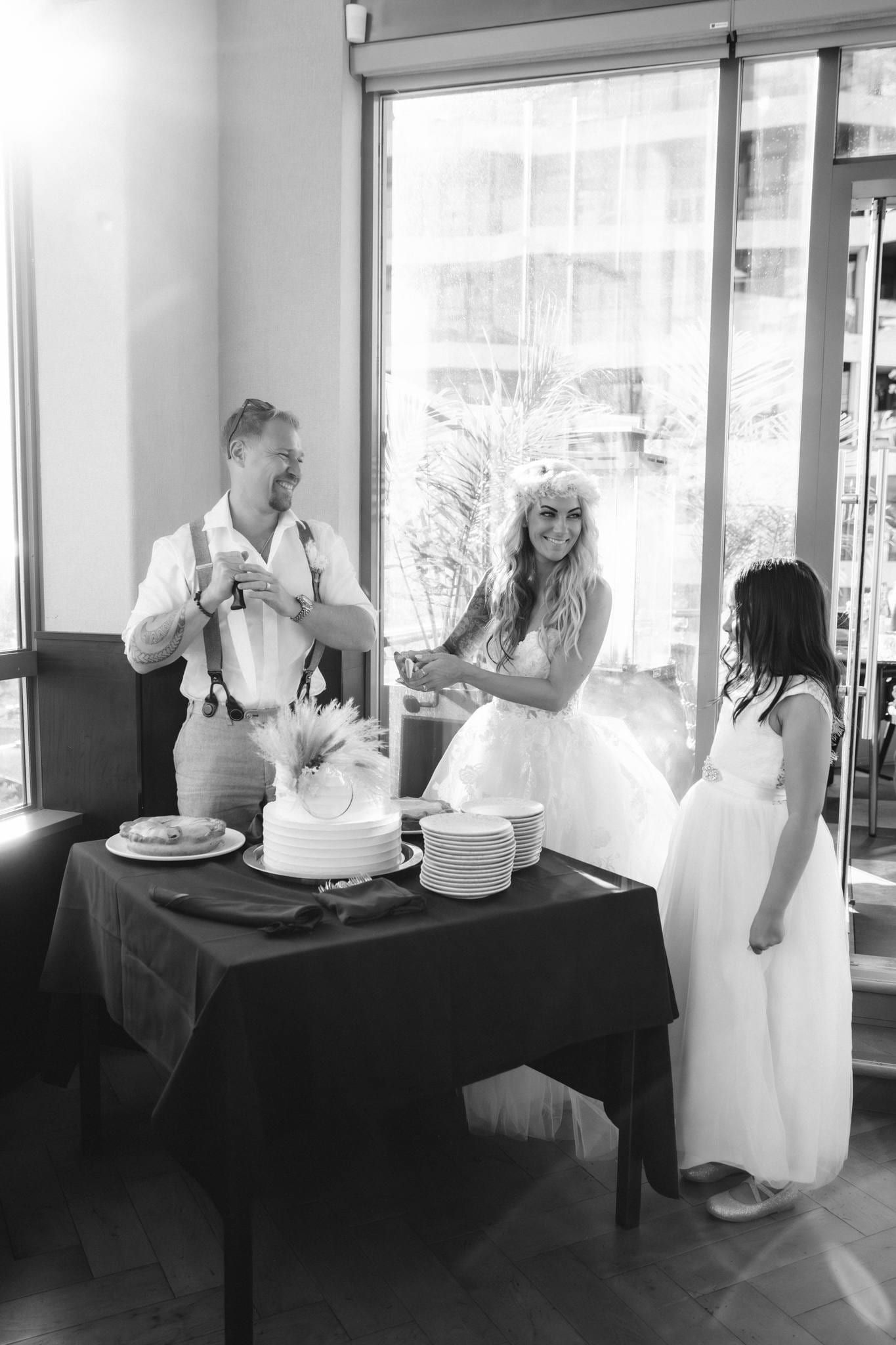 Black-and-white photo of the couple with a guest at the reception table