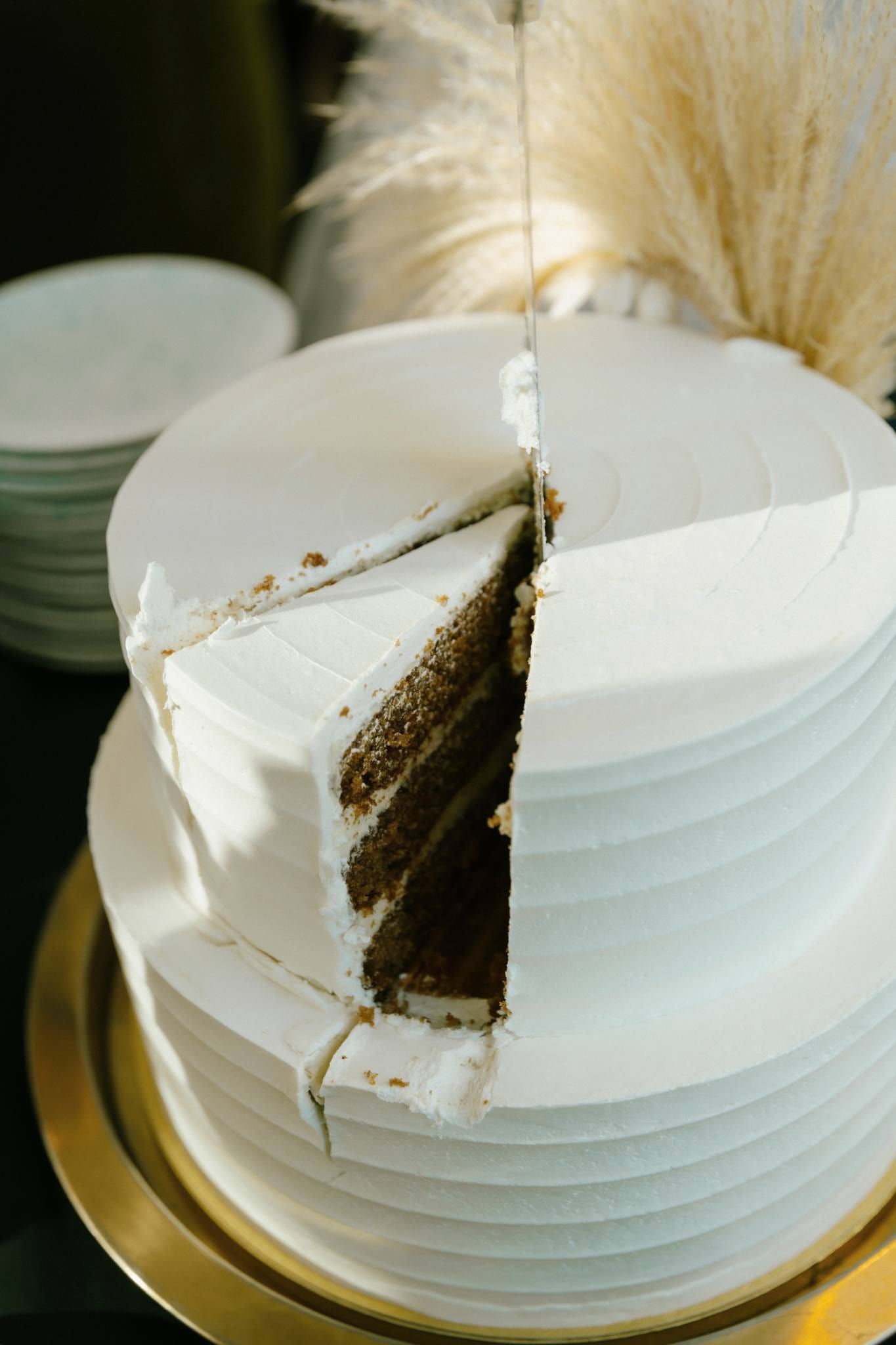 Sliced wedding cake topped with pampas grass