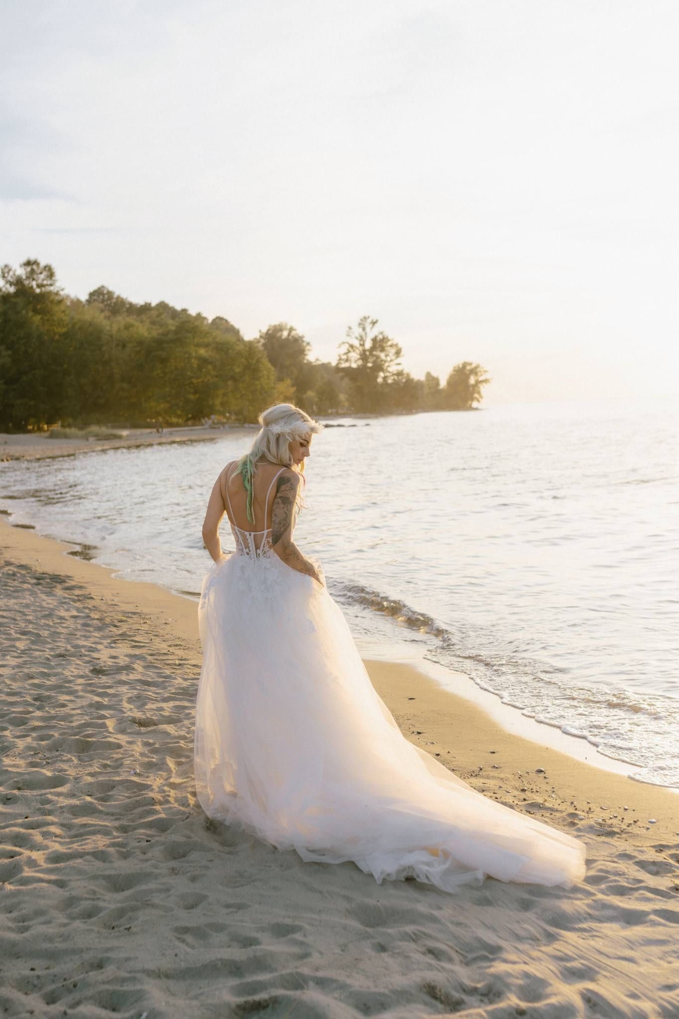 Bride walking along the shoreline with her train trailing in the sand