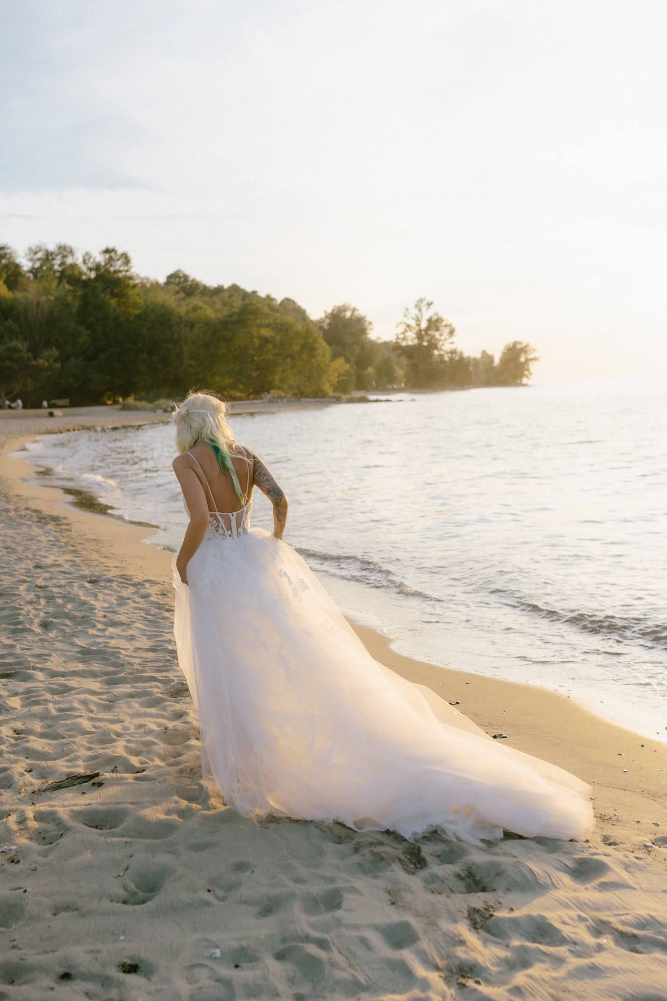 Bride standing at the water's edge, her train spread on the sand
