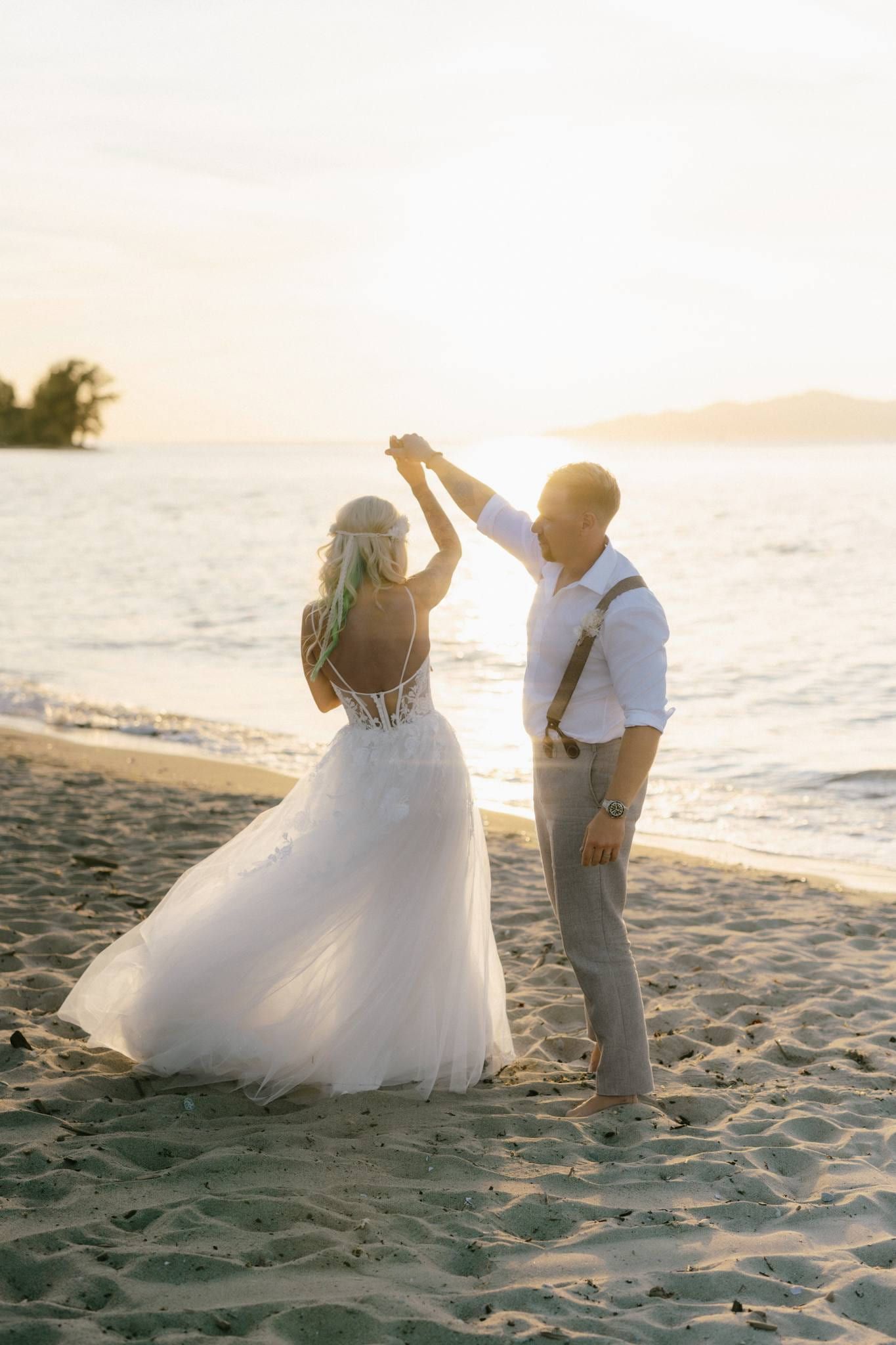 Groom twirling the bride on the beach at sunset