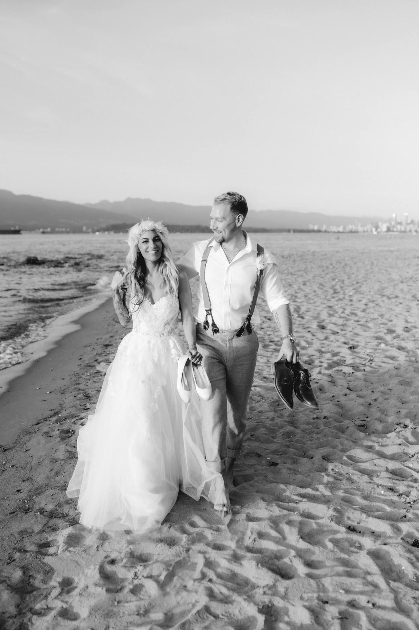 Black-and-white photo of the couple walking barefoot along the beach