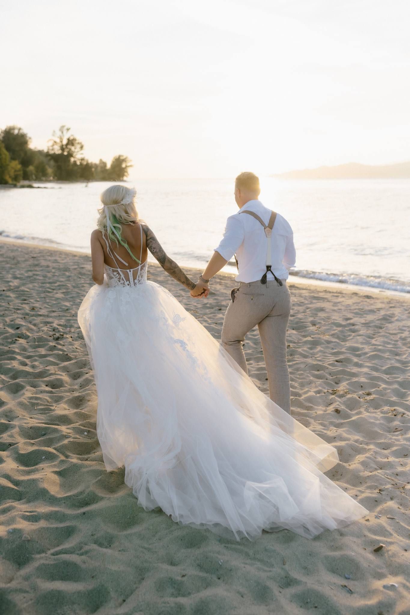 Couple walking hand in hand along the sand at sunset