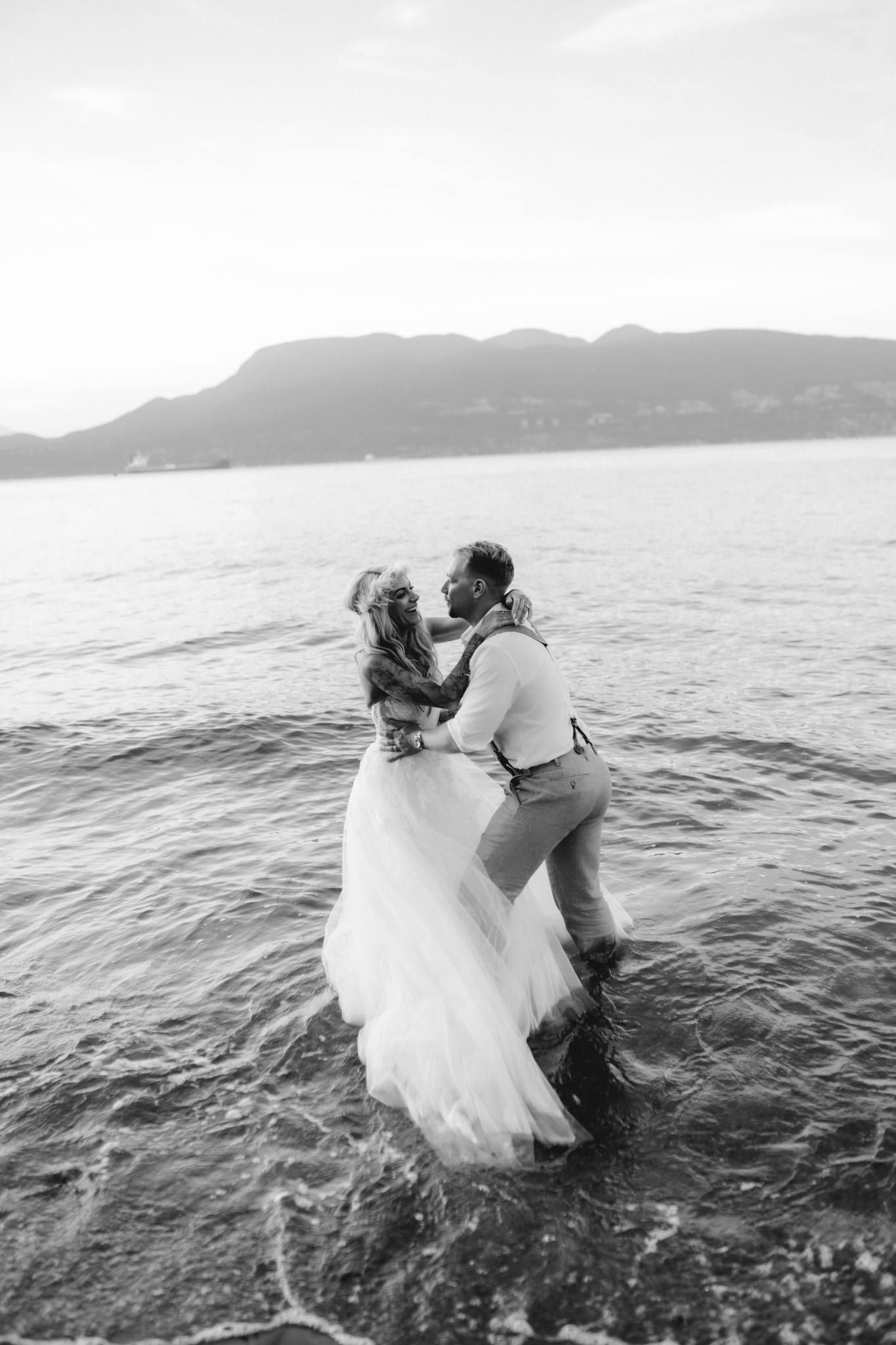 Black-and-white photo of the couple embracing in the shallows