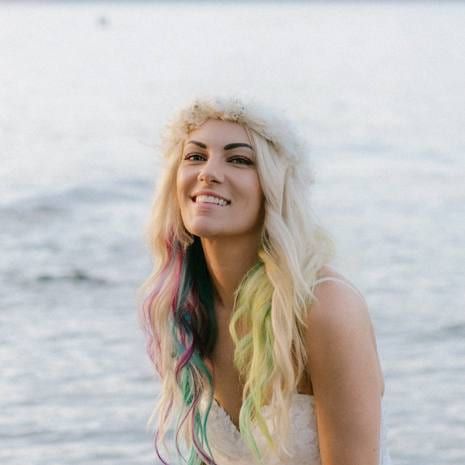 Whitney in a flower crown smiling by the sea