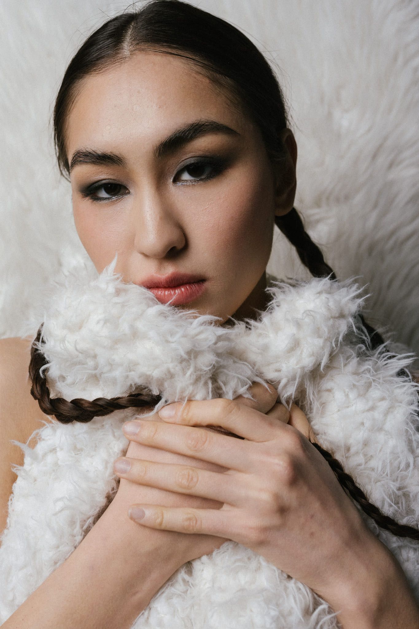 Moody portrait photography, close-up portrait of a woman with braids wrapped in white faux fur