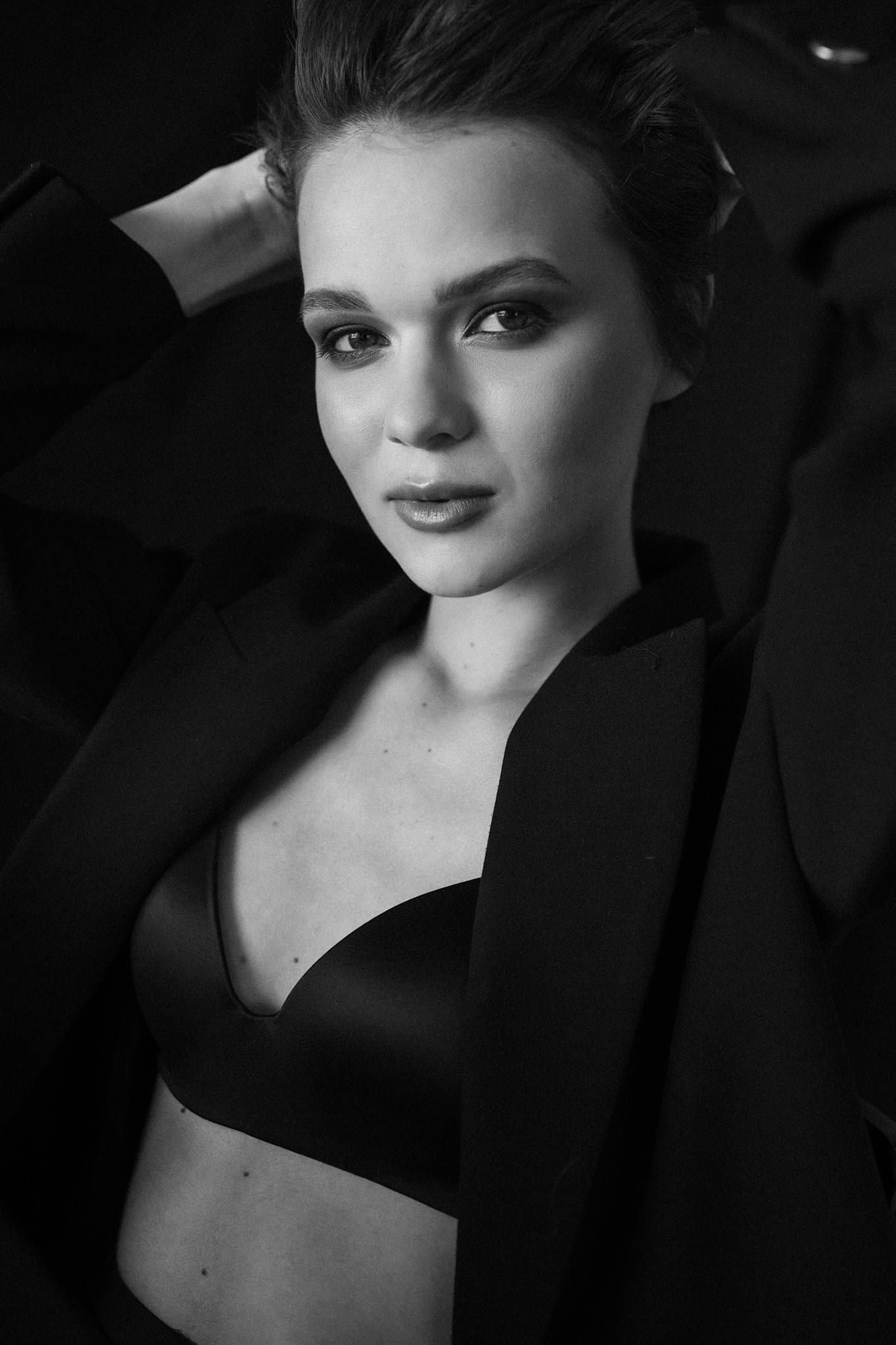 Studio portrait of a model in a black bra and blazer, arms folded